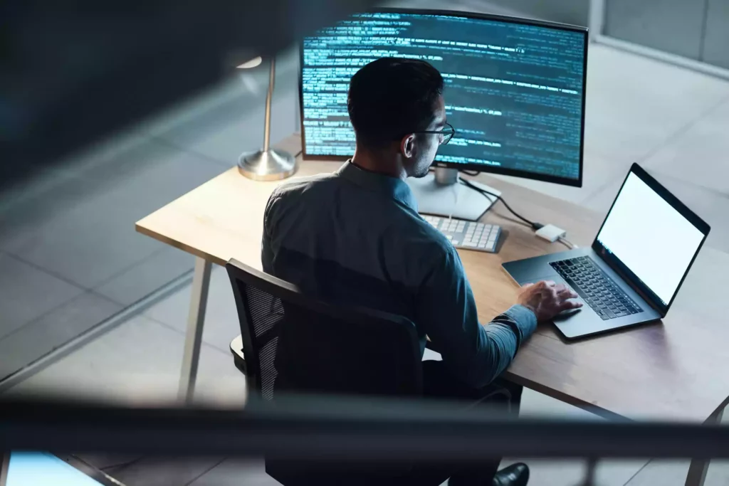 Homme derrière un bureau en train de travailler sur son ordinateur