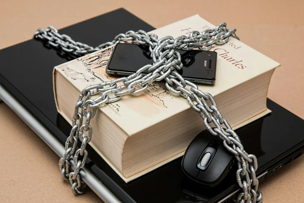 Livre, smartphone et ordinateur enchaînés, représentant la sécurité informatique.